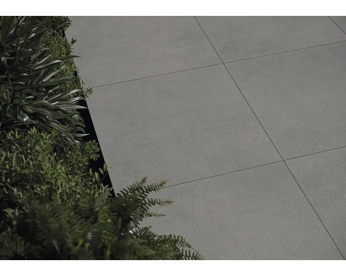 Pokládka terasových dosiek vedľa zelených rastlín.