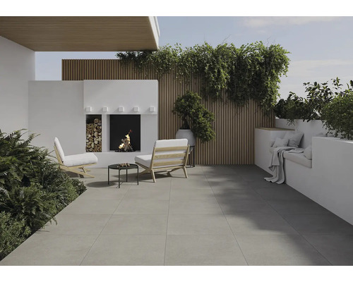 Terasa s kamennou podlahou, sedením, krbom a rastlinami pre útulnú vonkajšiu atmosféru