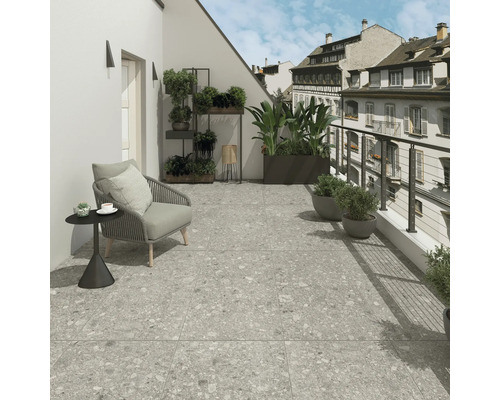 Balkón so sivou dlažbou, stoličkou a rastlinami