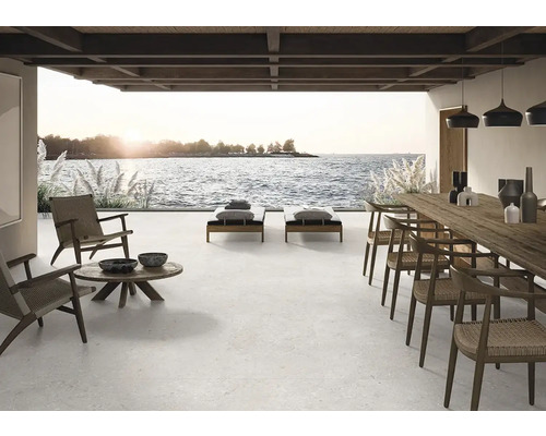 Veľká terasa s dlažbou, ležadlami, stolom a stoličkami s výhľadom na more.