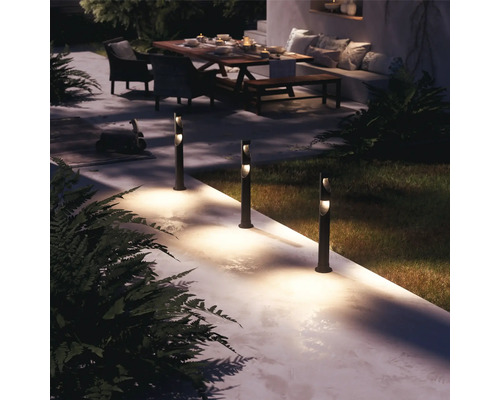 Osvetlený záhradný chodník s stĺpikovými svietidlami, posedenie v pozadí.