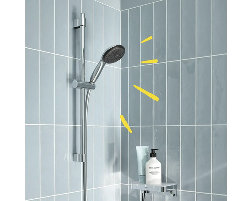 Sprchová hlavica na sprchovej tyči s poličkou na kúpeľňové doplnky pred sivými dlaždicami