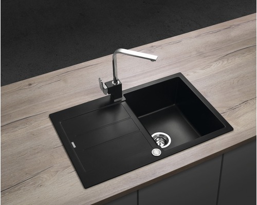 Čierny kuchynský drez s odkvapkávacou plochou a vodovodnou batériou na pracovnej doske