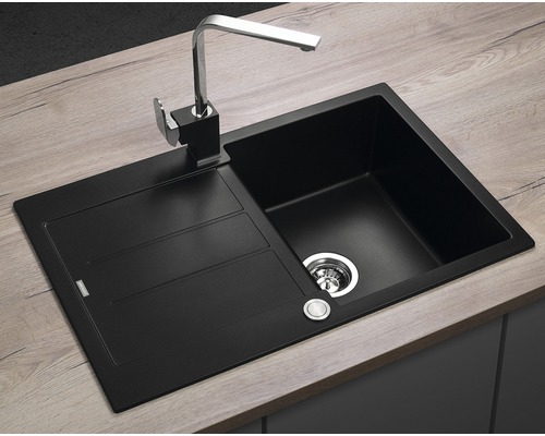 Čierny kuchynský drez s odkvapkávacou plochou a batériou na pracovnej doske.