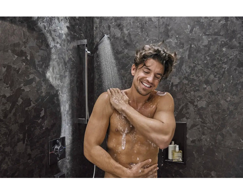 Muž v sprche s nástenným termostatom a hornou sprchou