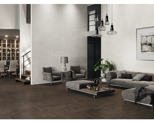 Priestranný obývací priestor s hnedou dlažbou a svetlými obkladmi stien, vybavený sivým nábytkom.