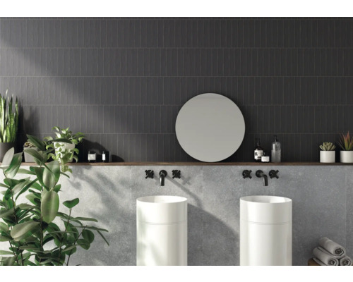 Kúpeľňa s tmavými obkladačkami, dvoma umývadlami, okrúhlym zrkadlom a dekoráciou