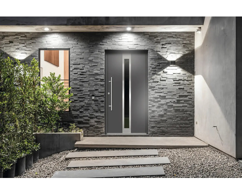 Moderný dom so sivými vchodovými dverami, kamennou stenou a dláždenou cestou