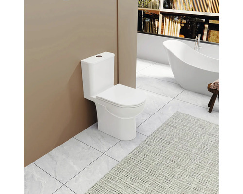 Biela stojaca toaleta v kúpeľni s vaňou a kobercom