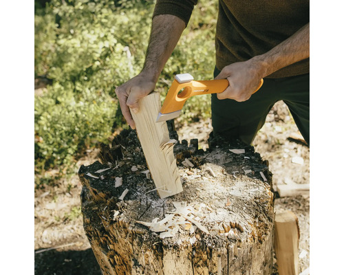 Osoba štiepe drevo štiepacou sekerou na kláte.