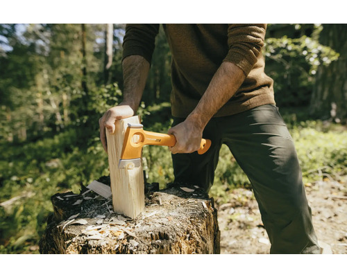 Muž štiepe drevo sekerou Fiskars na pni