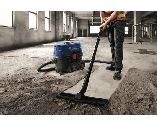 Remeselník čistí stavenisko priemyselným vysávačom Bosch.