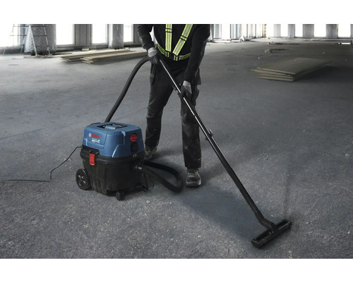 Muž používa priemyselný vysávač Bosch na upratovanie hrubej stavby.