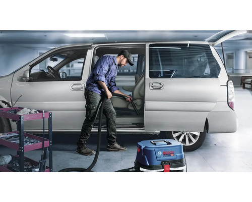 Muž čistí interiér auta vysávačom Bosch Professional.