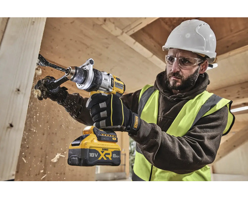 Remeselník vŕta otvor do drevenej dosky pomocou akumulátorovej vŕtačky DeWalt