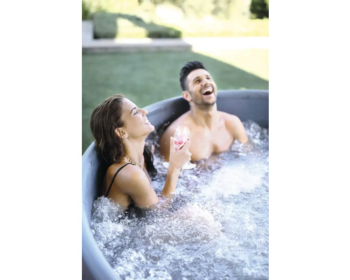 Dvaja ľudia sa smejú a relaxujú v kúpacej kadi v záhrade.