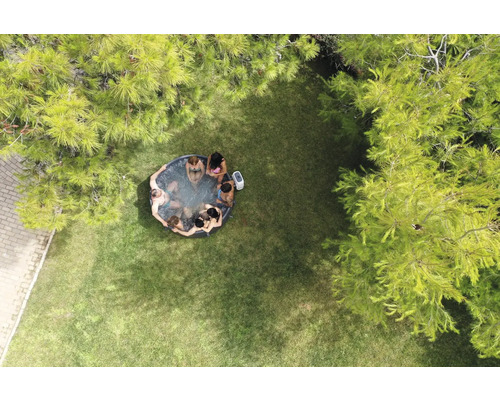 Letecký pohľad na záhradu s nafukovacou vírivkou, v ktorej sedí niekoľko ľudí.