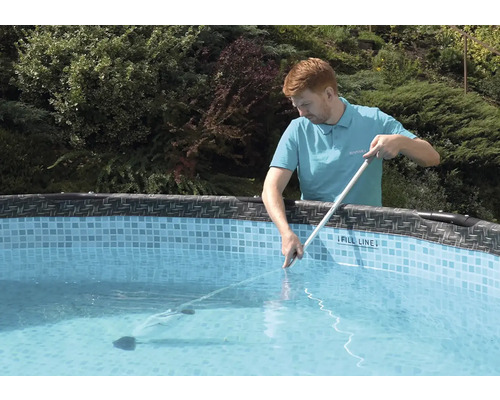 Muž čistí bazén pomocou čističa bazénu a tyče