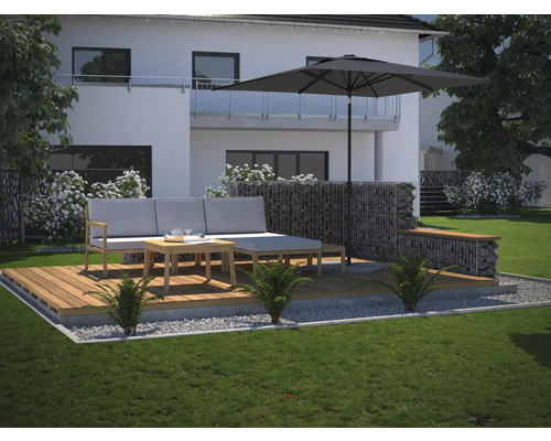 Moderná terasa s drevenou palubovkou, sivou sedacou súpravou, slnečníkom a gabionovým múrom v záhrade.