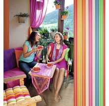 Dve ženy pijú kávu na balkóne s farebnou výzdobou a lamelovým závesom.