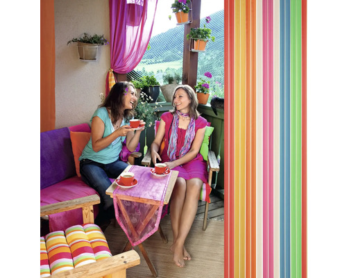 Dve ženy pijú kávu na balkóne s farebnou výzdobou a lamelovým závesom.