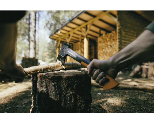 Sekera štiepe drevo na kláte vonku.