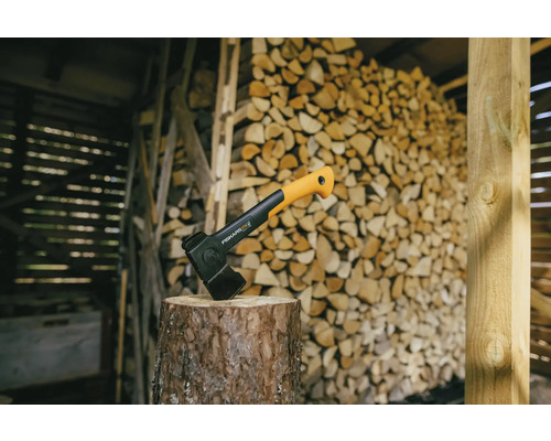 Štiepacia sekera na kláte pred hromadou dreva