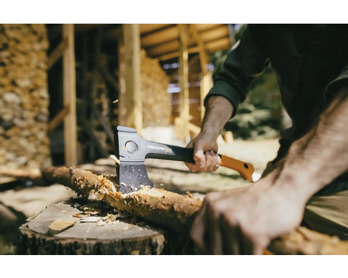 Muž štiepa drevo sekerou Fiskars na pni.