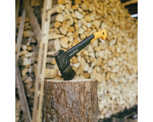 Štiepací kladivo na pni pred hromadami dreva