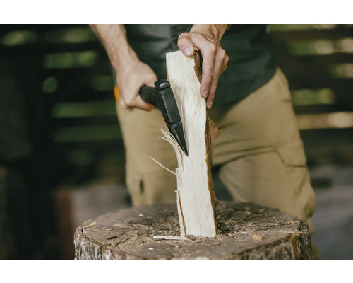 Muž štiepa drevo štiepacou sekerou na kláte