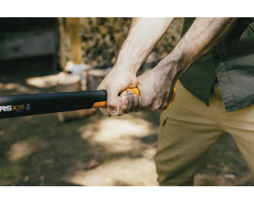 Osoba drží štiepaciu sekeru Fiskars na štiepanie dreva.