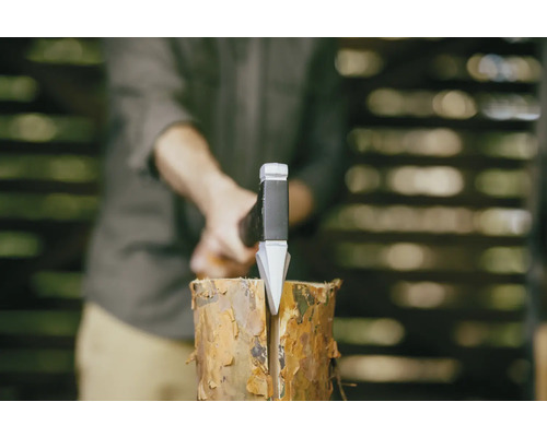 Muž štiepe klát dreva štiepacou sekerou.