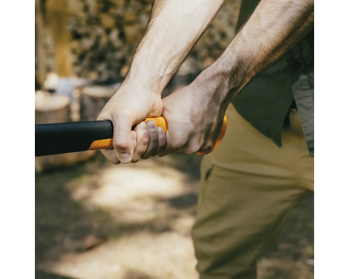 Detailný záber osoby držiacej sekeru s čiernou hlavou a oranžovou rukoväťou