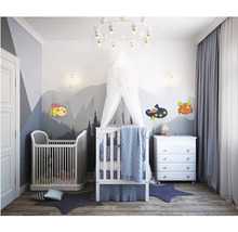 Svetlá detská izba s detskými postieľkami, komodou a dekoratívnymi nálepkami na stenu.