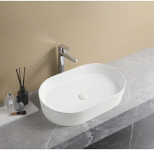 Oválne umývadlo na doske s batériou v kúpeľni.