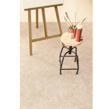 Detailný pohľad na svetlý koberec v ateliéri so stojanom, stoličkou a maliarskymi potrebami.