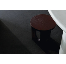 Detailný pohľad na čierny koberec s dreveným odkladacím stolíkom