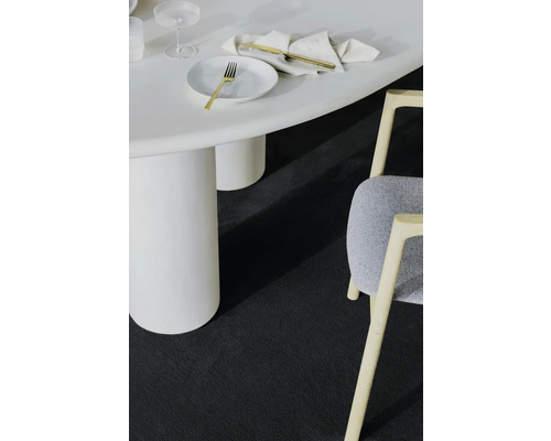 Detailný záber miestnosti s bielym stolom, stoličkou a tmavým kobercom