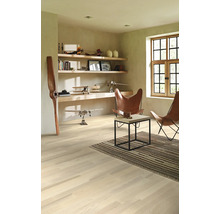 Svetlá miestnosť s drevenou podlahou, policami, dekoráciou a dvoma koženými kreslami