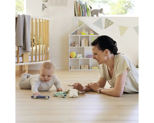 Dieťa sa hrá s dospelou ženou a autíčkami na drevenej podlahe vo svetlej miestnosti vhodnej pre deti.