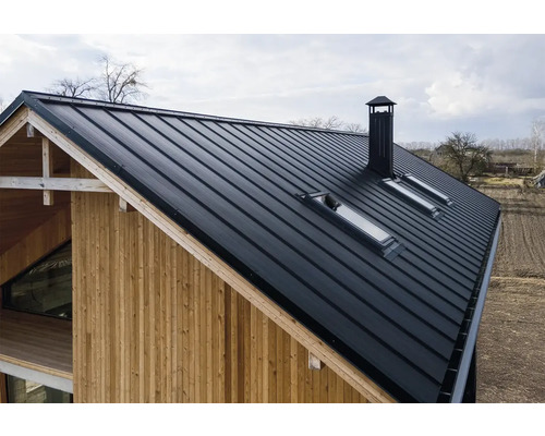 Pohľad na dom s plechovou strechou, strešnými oknami a komínom.