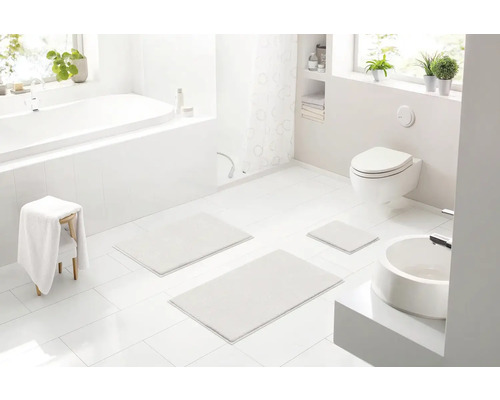 Svetlá kúpeľňa s vaňou, toaletou, umývadlom a tromi kúpeľňovými kobercami