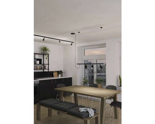 Moderná kuchyňa s čiernou kuchynskou linkou, dreveným stolom, lavicou s vankúšmi a koľajnicovým systémom so spotmi na osvetlenie
