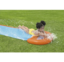 Dievča sa šmýka na vodnej šmýkačke v záhrade.