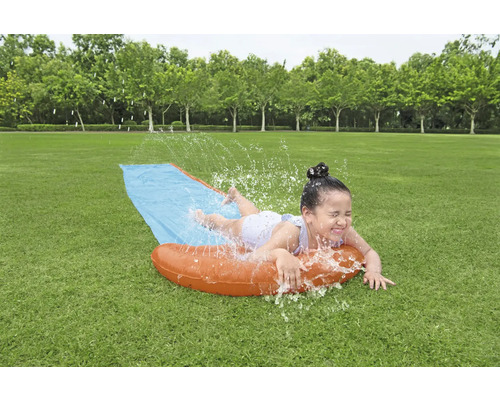 Dievča sa zabáva na vodnej šmykľavke v záhrade