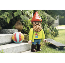 Hračka záhradného trpaslíka s bradou, čiapkou a dekoráciami v záhrade