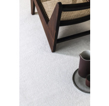 Detailný záber svetlého koberca so stoličkou a riadom