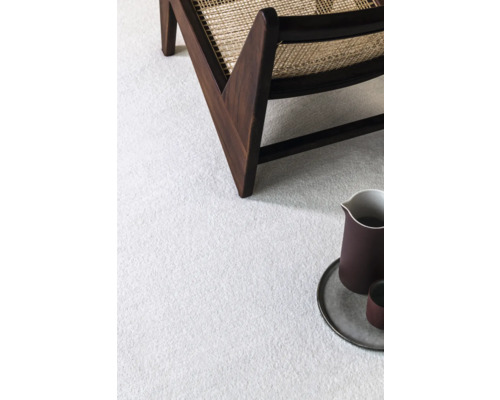 Detailný záber svetlého koberca so stoličkou a riadom