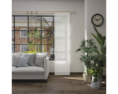 Obývacia izba s pohovkou, izbovými rastlinami, hodinami a posuvným panelom pred oknom