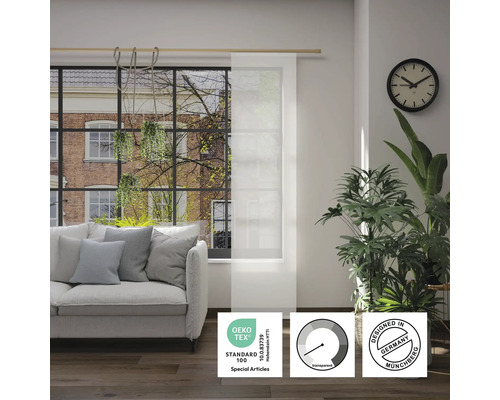 Obývacia izba s pohovkou a priehľadným panelovým závesom s pečaťou Öko-Tex Standard 100, symbolom priehľadnosti a pečaťou Designed in Germany.